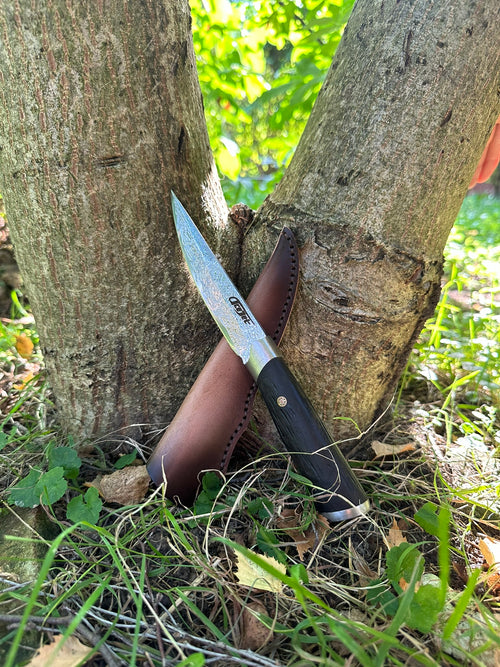 ACEJET MIRIS jachtmes tegen een boomstam in het bos, met leren schede